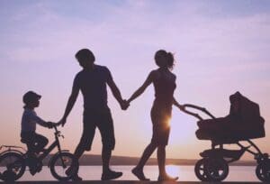 A shadowed family walking against a sunset, demonstrating the idea of capturing familial data when doing customer acquisition.